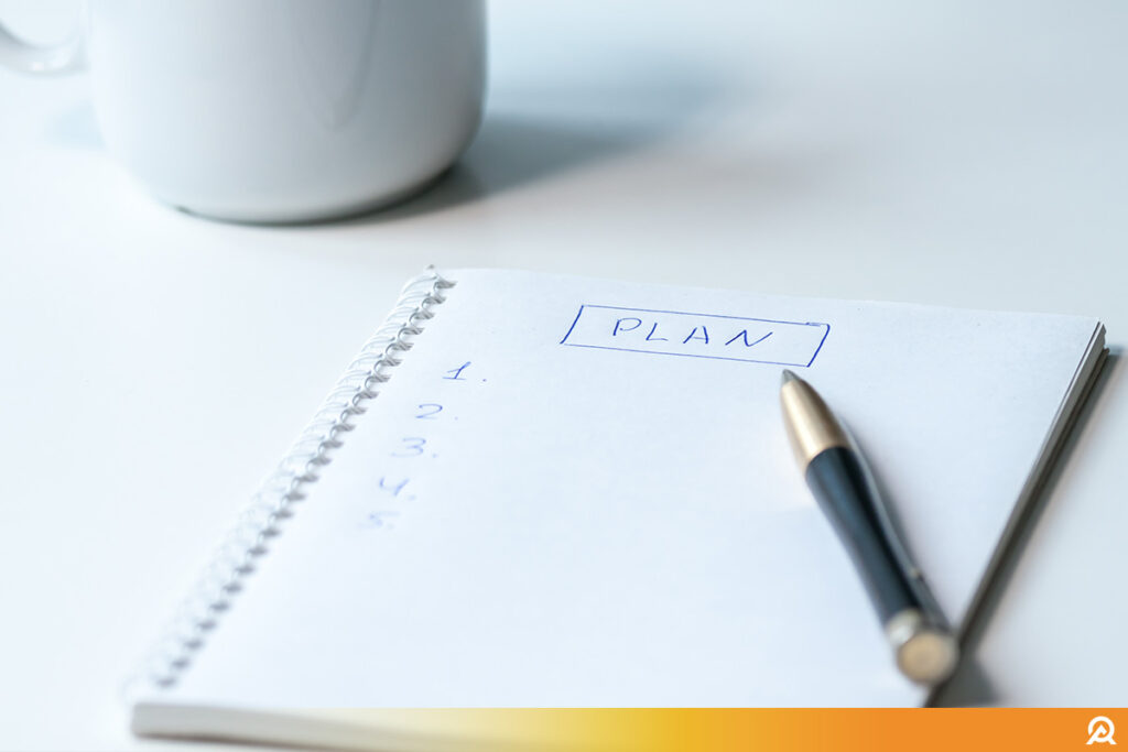 Document manuscrit intitulé 'plans d'actions' placé dans un panier en osier, sur fond blanc, symbolisant une organisation artisanale ou non digitalisée